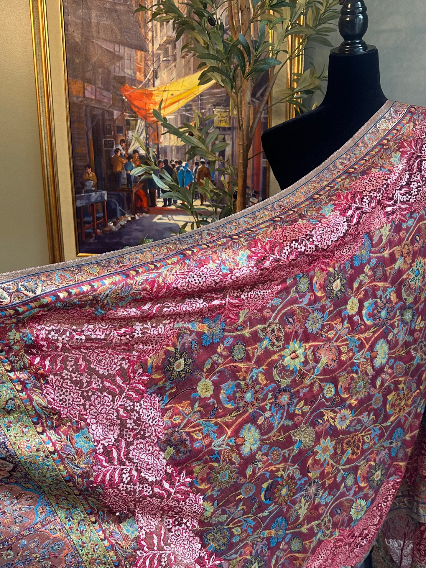 Floral patterned fabric draped over a mannequin against a wall with a painting.