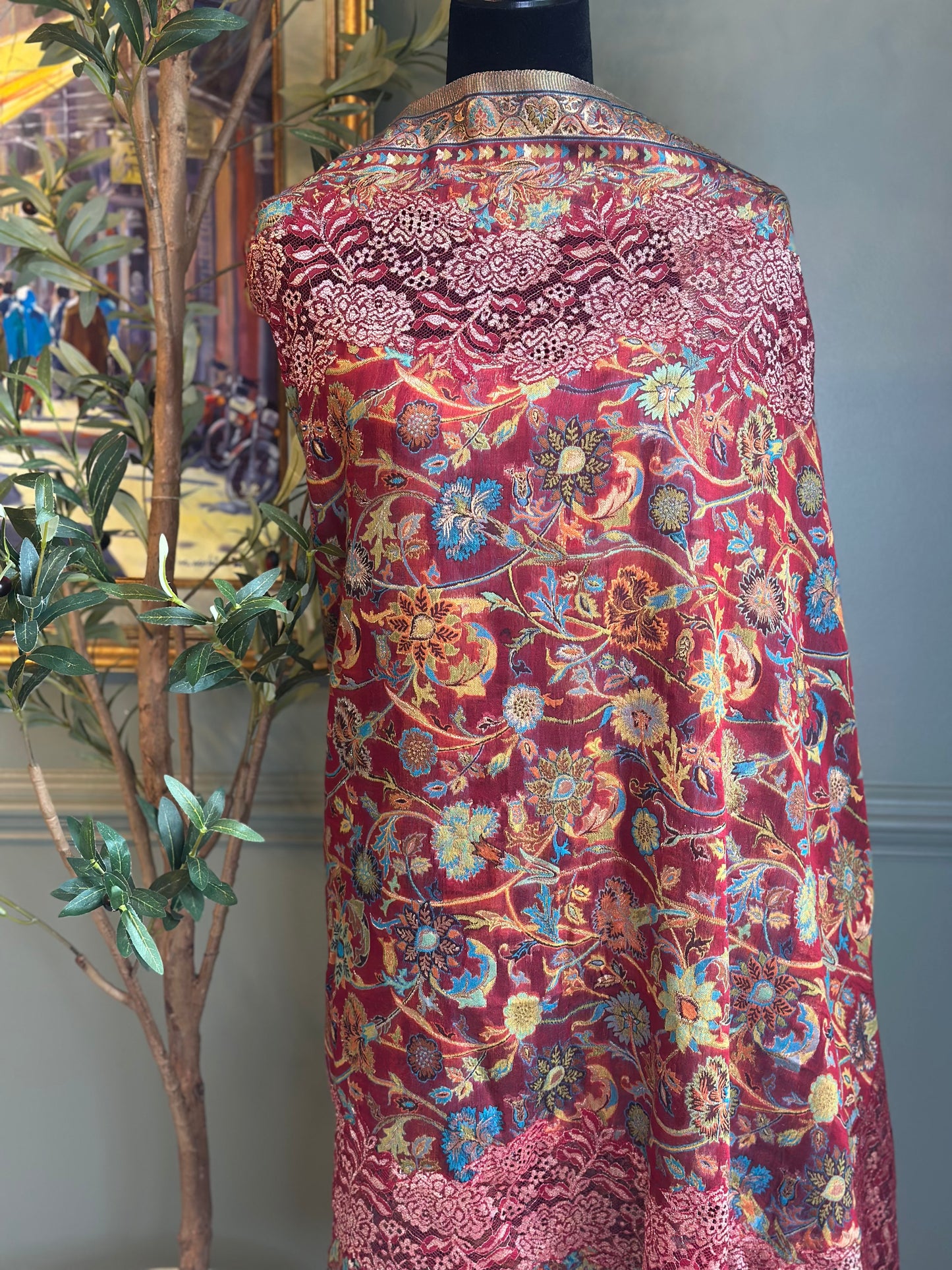 Red patterned fabric on a mannequin with a plant in the background