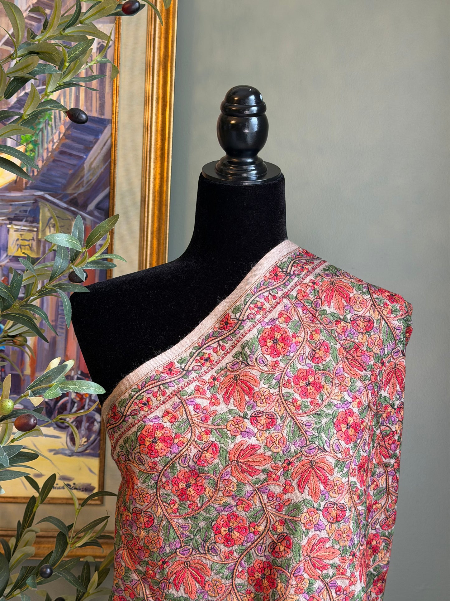 Mannequin wearing a floral shawl with a decorative background