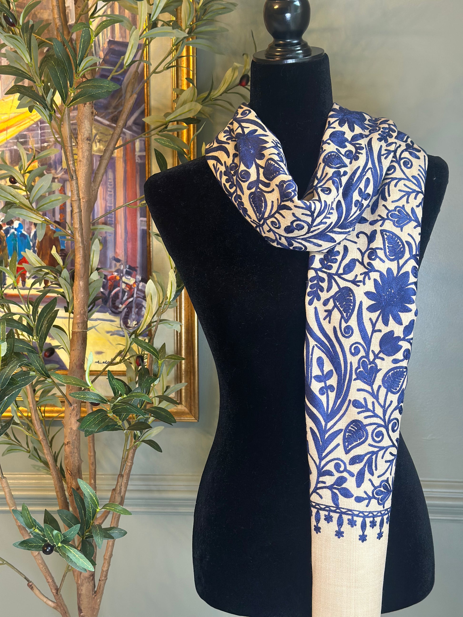 Blue and white patterned scarf on a black mannequin against a decorative background