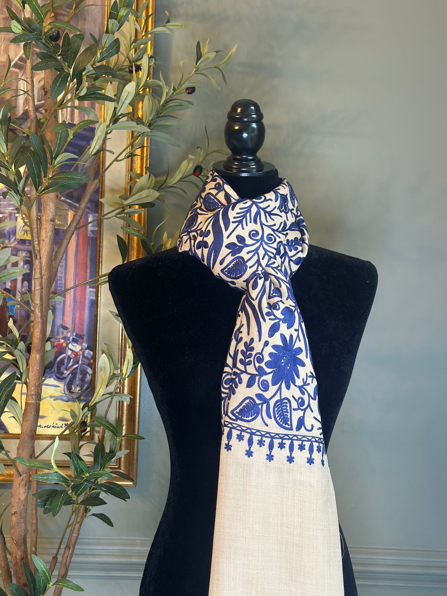 Mannequin wearing a white scarf with blue floral patterns against a neutral background