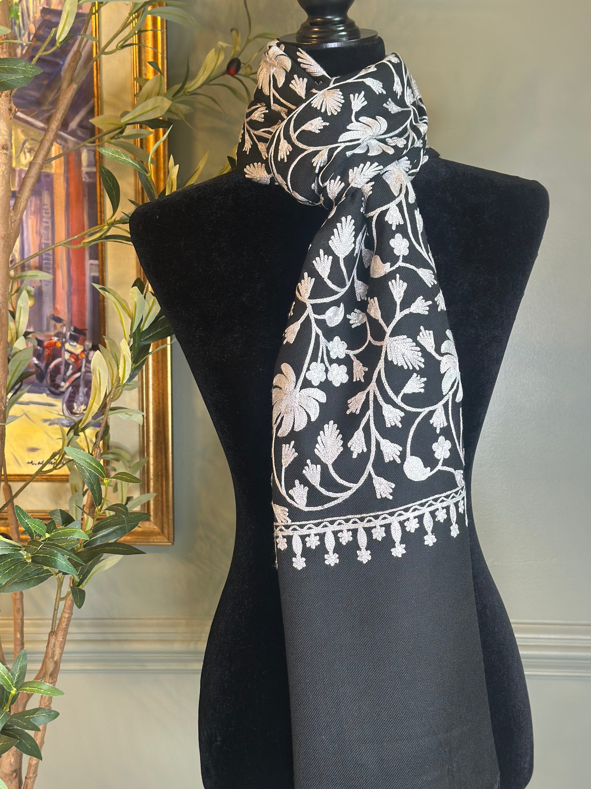 Black scarf with white floral patterns draped over a mannequin against a neutral background.