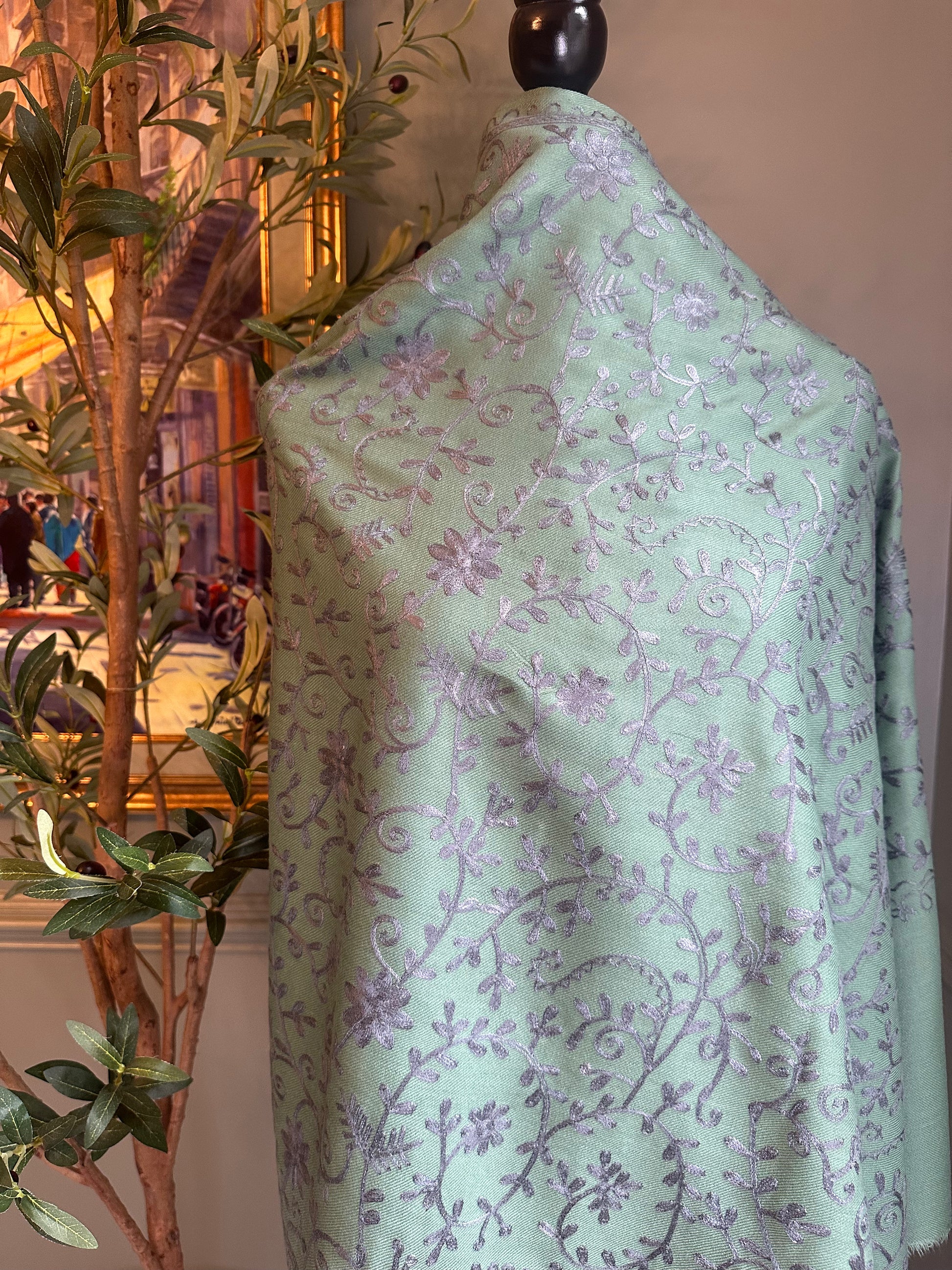 Light green fabric with purple floral pattern on a mannequin against a neutral background