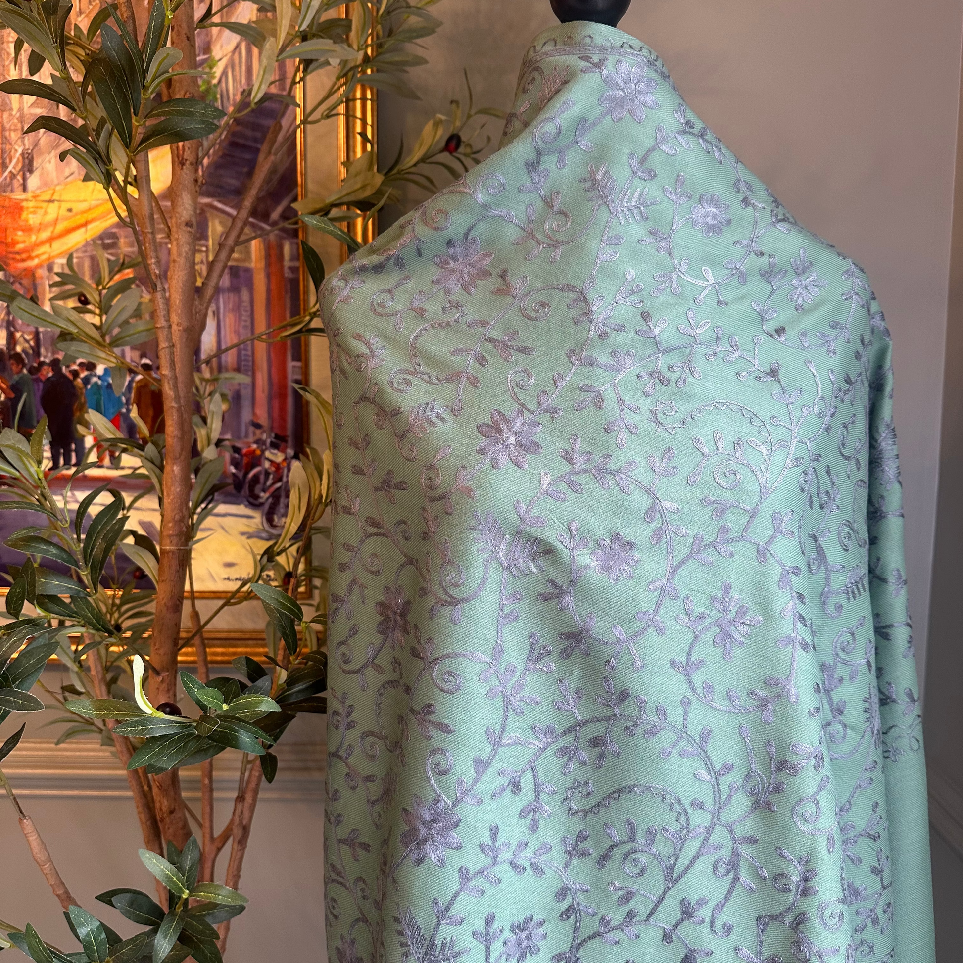 Light green fabric with purple floral pattern on a mannequin against a blurred indoor background