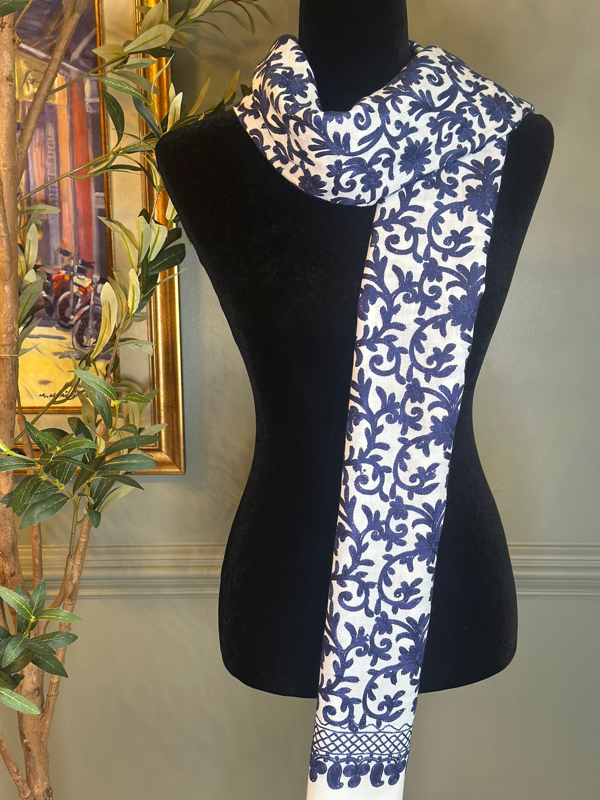 Blue and white patterned scarf on a black mannequin against a neutral background