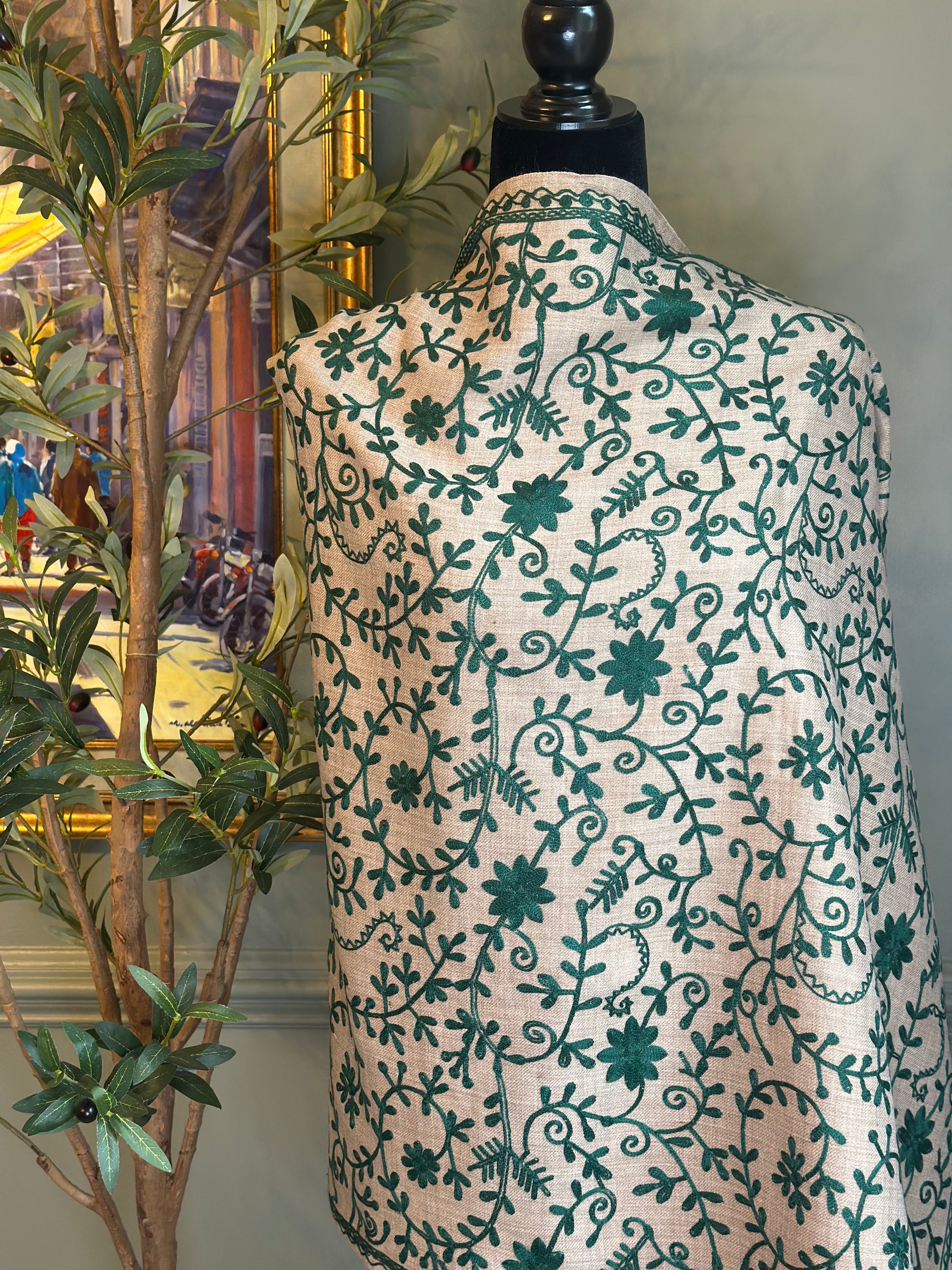 Mannequin wearing a patterned wrap with green floral design against a neutral background