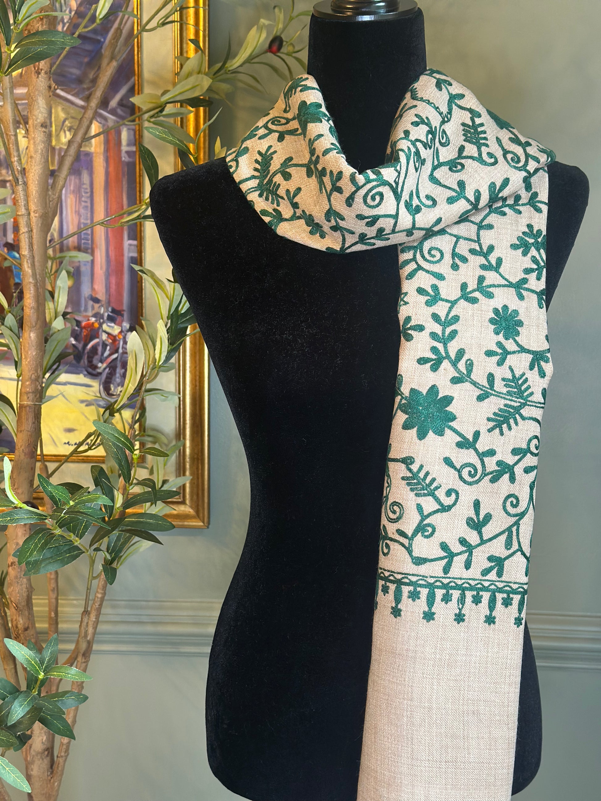 Scarf with green floral pattern draped over a black mannequin against a neutral background.