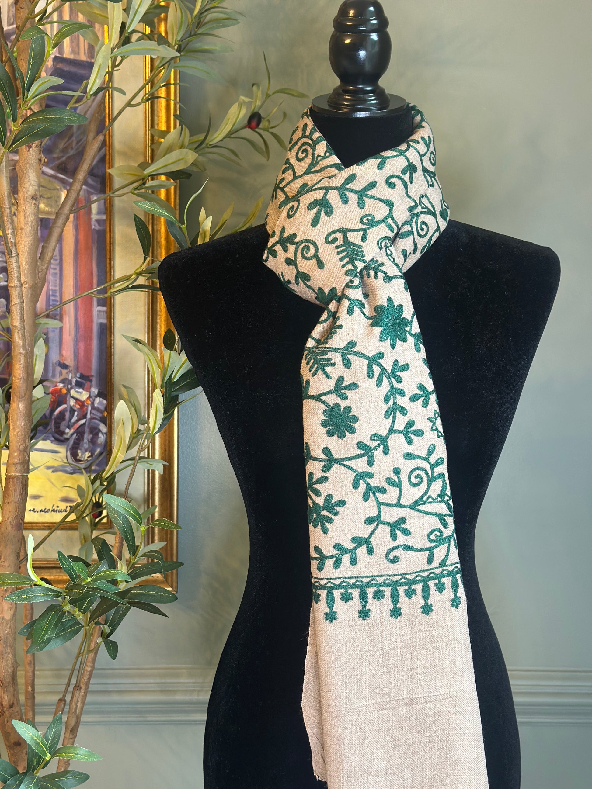 Scarf with green floral pattern on a black mannequin against a neutral background