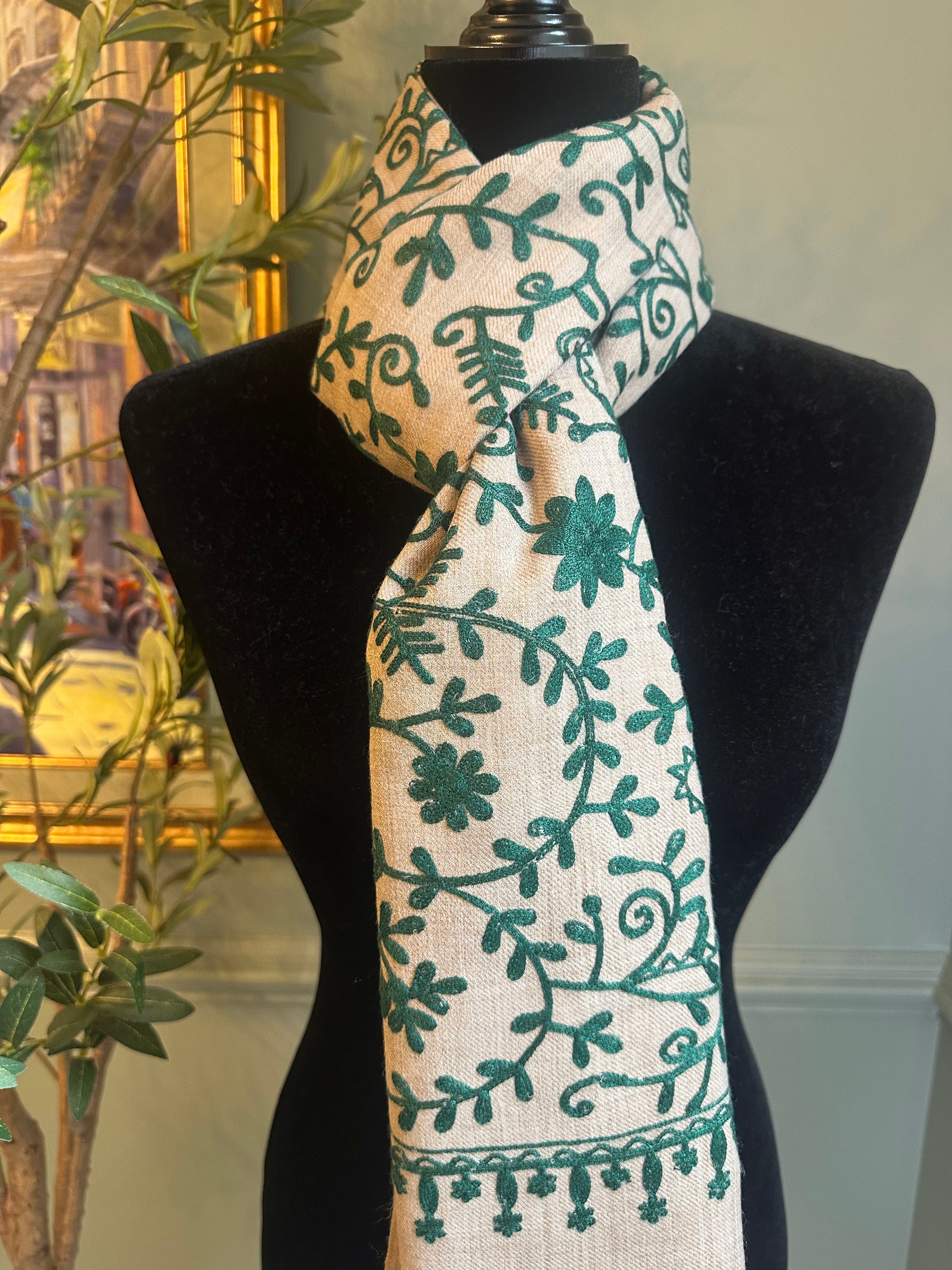 Scarf with green floral pattern on a mannequin against a neutral background
