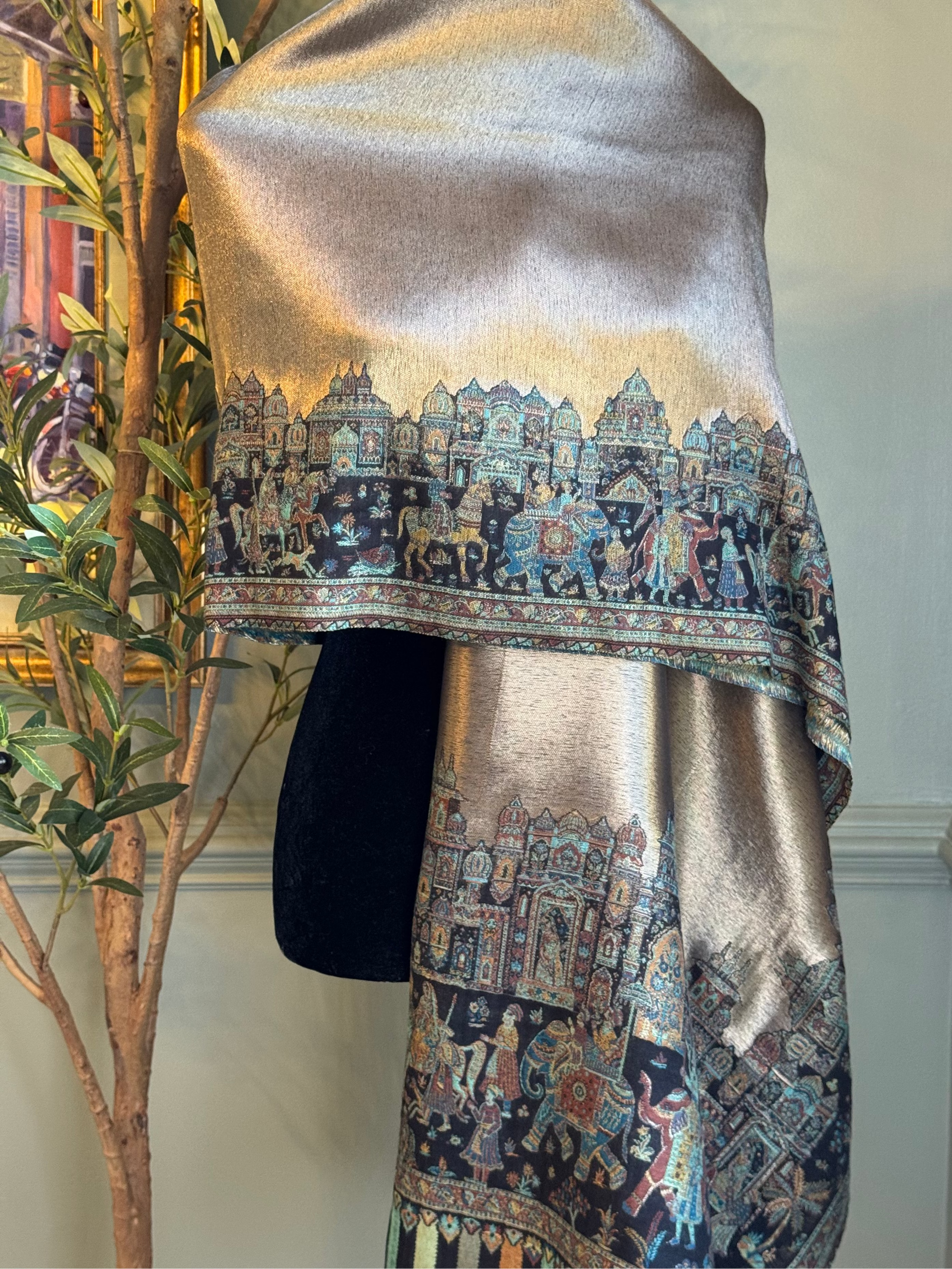 Decorative shawl with intricate patterns draped over a mannequin against a neutral wall.