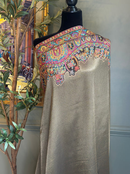 Mannequin wearing a gold shawl with colorful embroidery in a room setting.