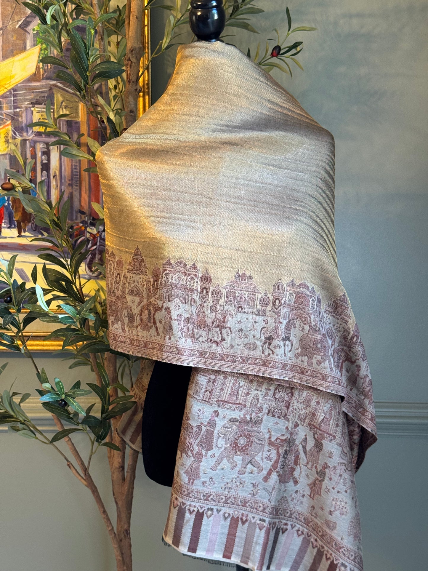 Mannequin wearing a beige and brown patterned scarf with a cityscape painting in the background