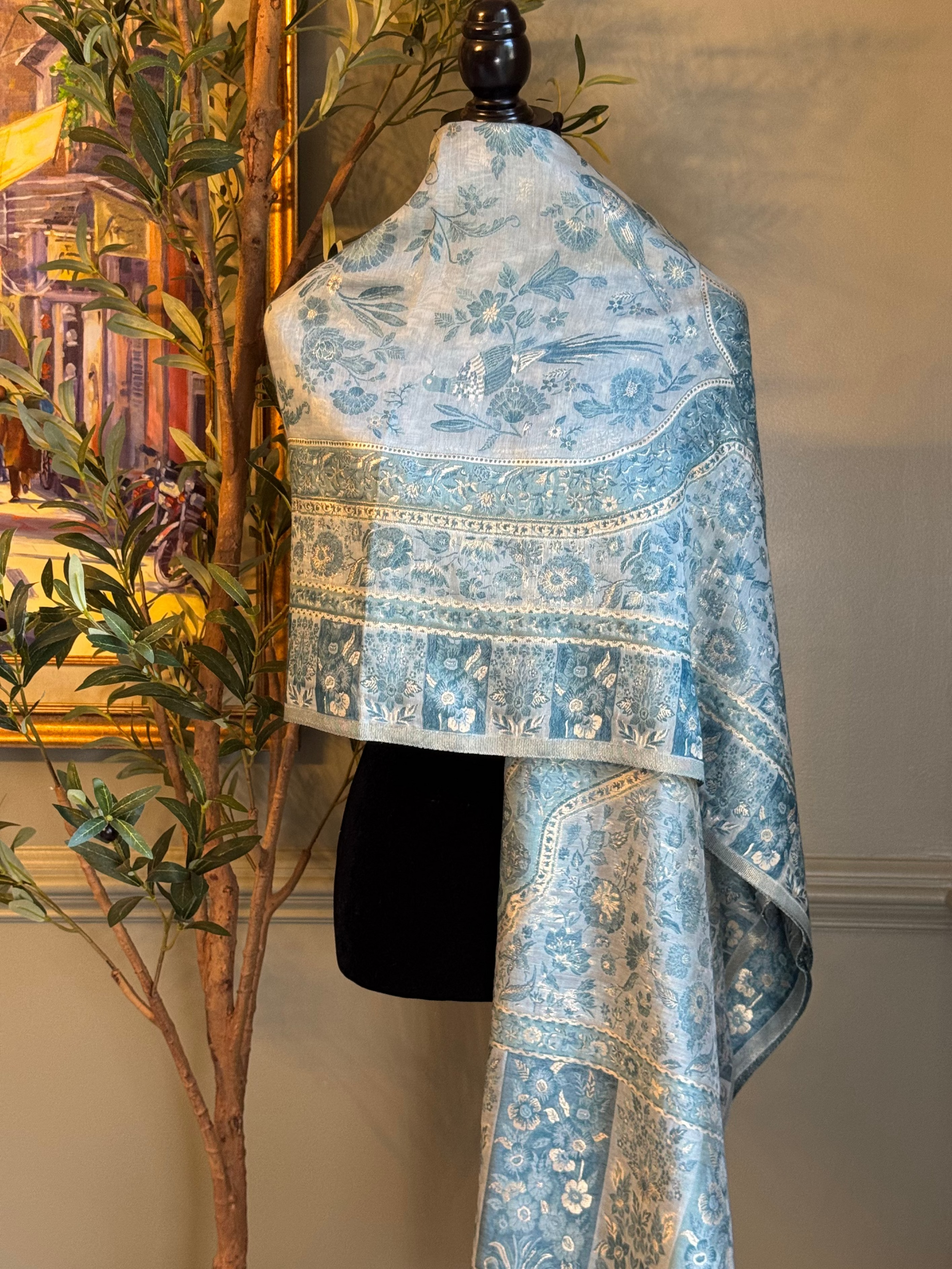 Blue floral patterned fabric on a mannequin against a neutral wall with a plant in the background
