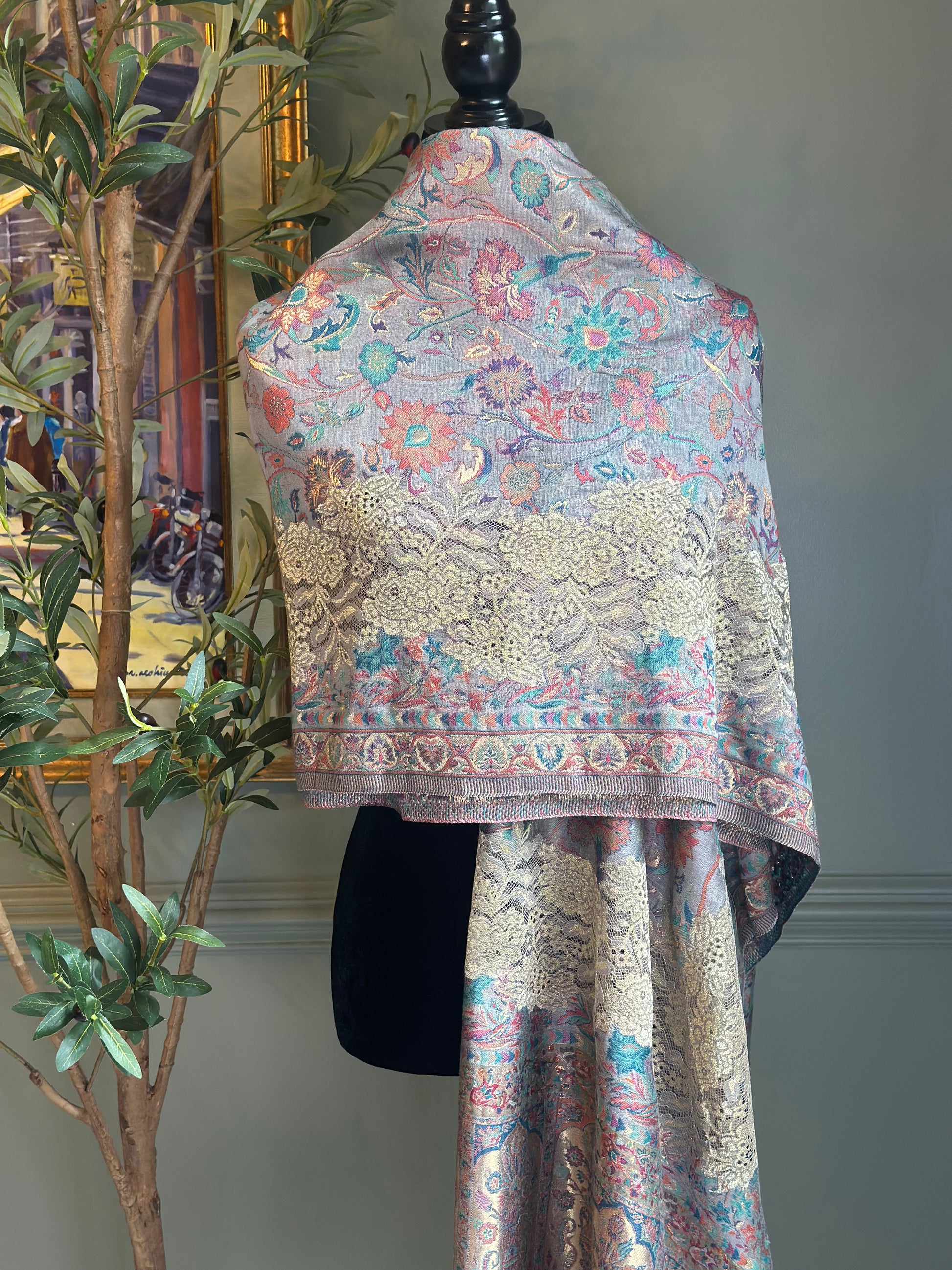 Decorative shawl with floral patterns draped over a mannequin against a neutral background.