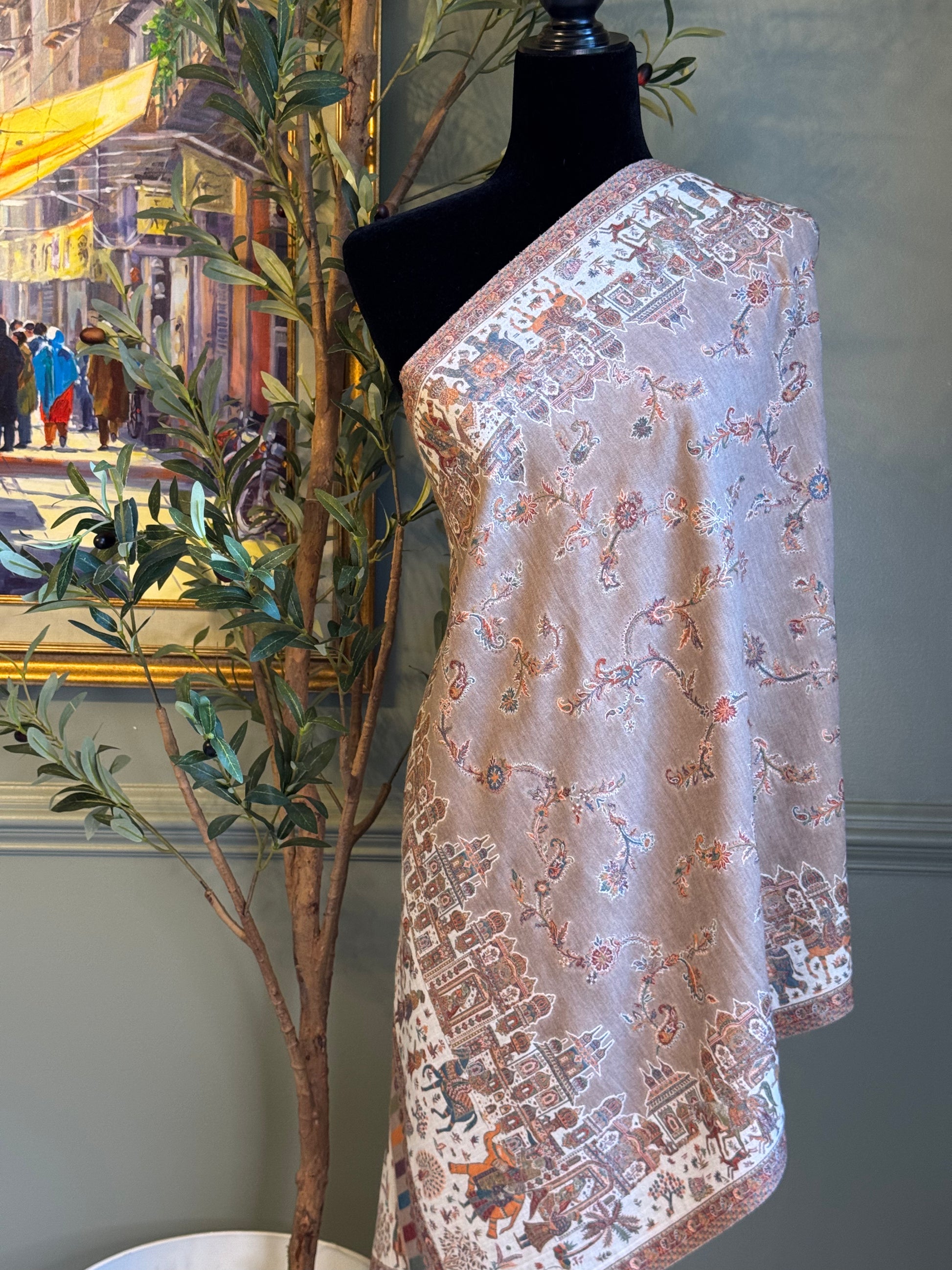 Patterned fabric on a mannequin against a decorative wall with a painting and plant.