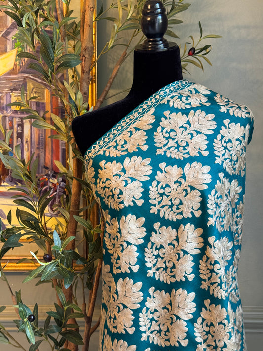 Mannequin wearing a blue embroidered garment with a decorative background