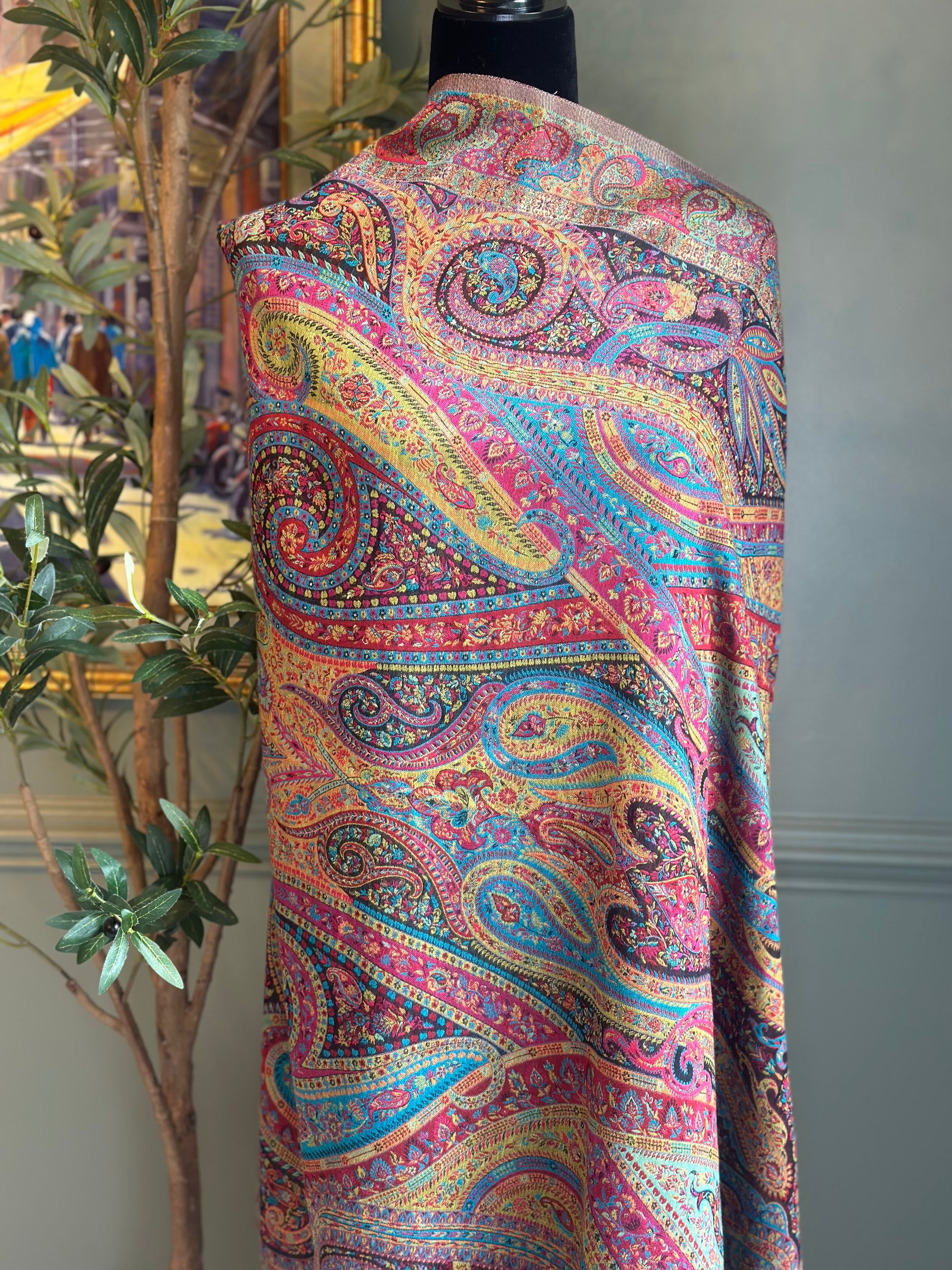 Colorful paisley-patterned fabric on a mannequin against a neutral wall.