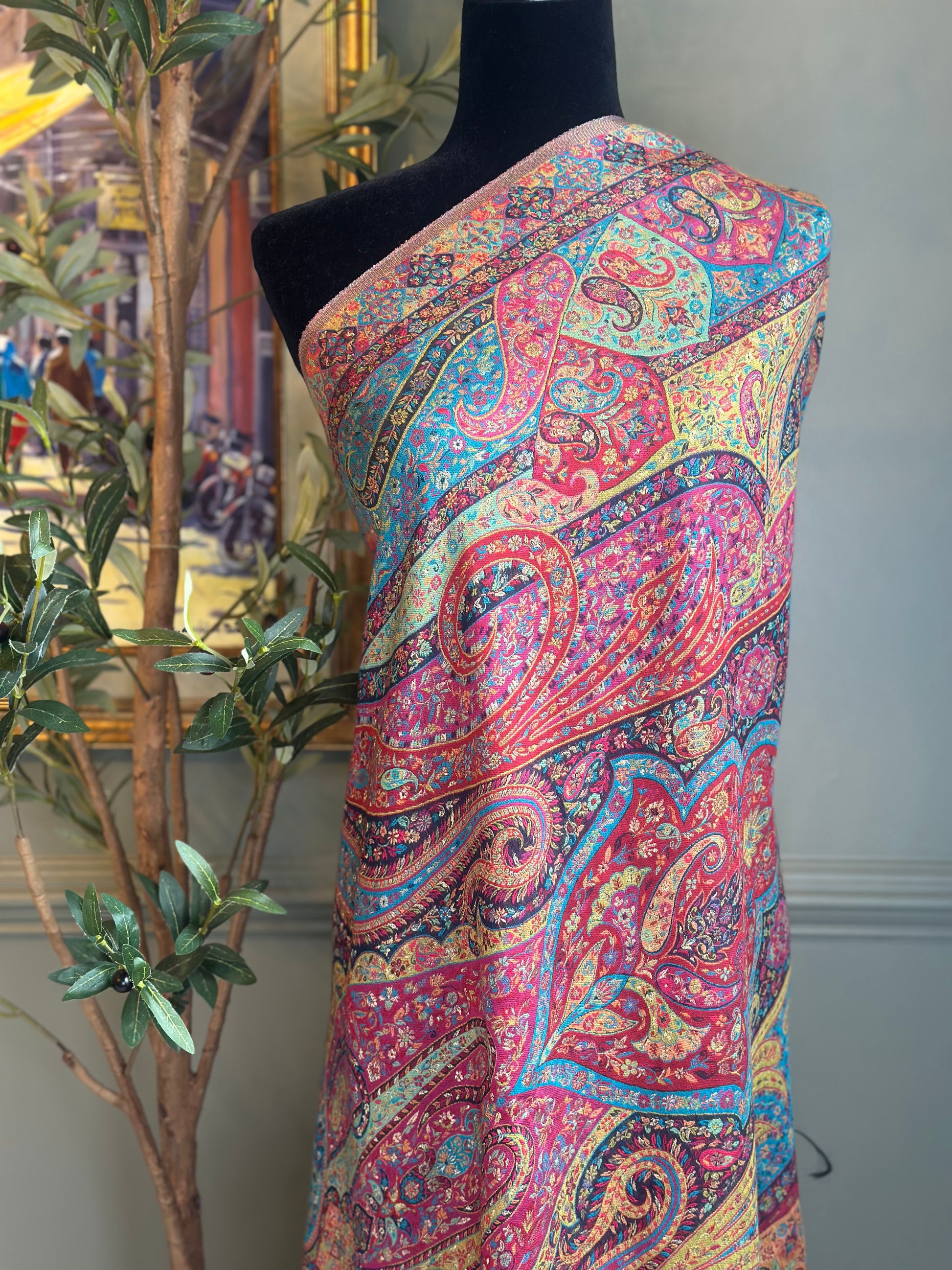 Colorful paisley patterned fabric draped over a mannequin against a neutral background.