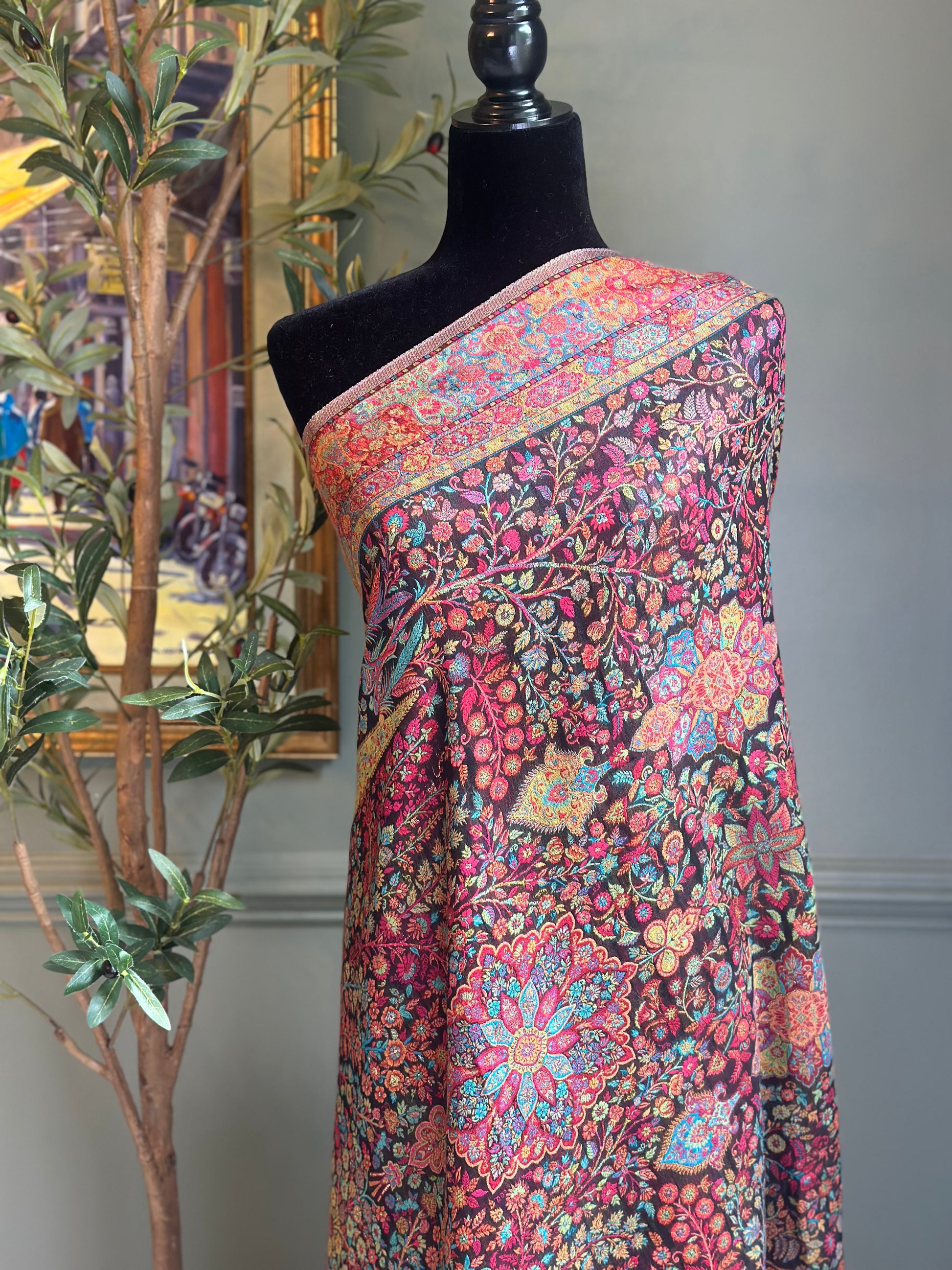 Colorful floral patterned shawl draped over a mannequin against a neutral background